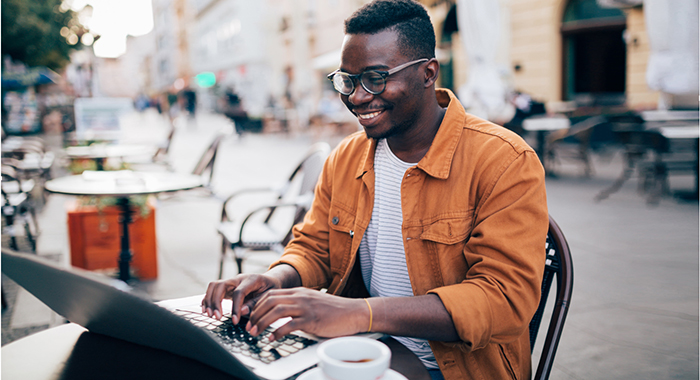 young man on a laptop outside, smiling